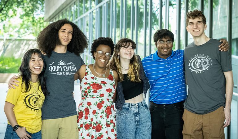 Six students embrace and smile for a photo.